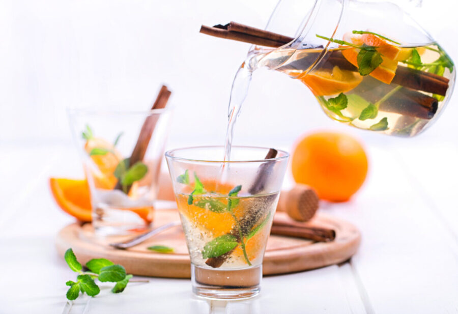 Tea with orange, mint and cinnamon on wooden white background